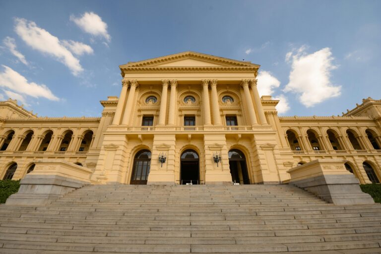 Stunning view of a neoclassical building with grand columns and stairs under a blue sky.