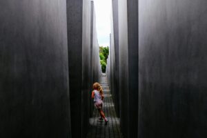 A young girl runs playfully through the narrow pathways of a modern concrete monument.