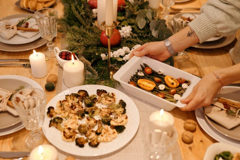 A beautifully set holiday dinner table with candles, vegetables, and festive decor.
