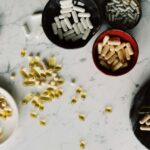 Assorted capsules and pills on a marble surface, illustrating healthcare and medication themes.