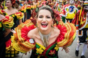 Smiling woman in colorful traditional attire at Barranquilla Carnival in Colombia.