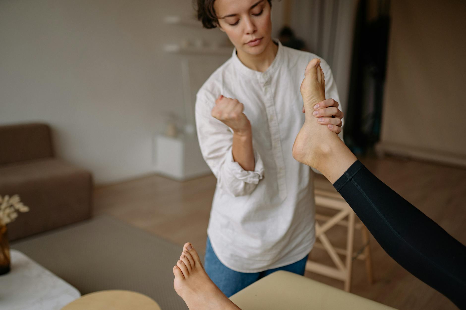 A massage therapist gives a relaxing foot therapy session in a calm indoor setting.