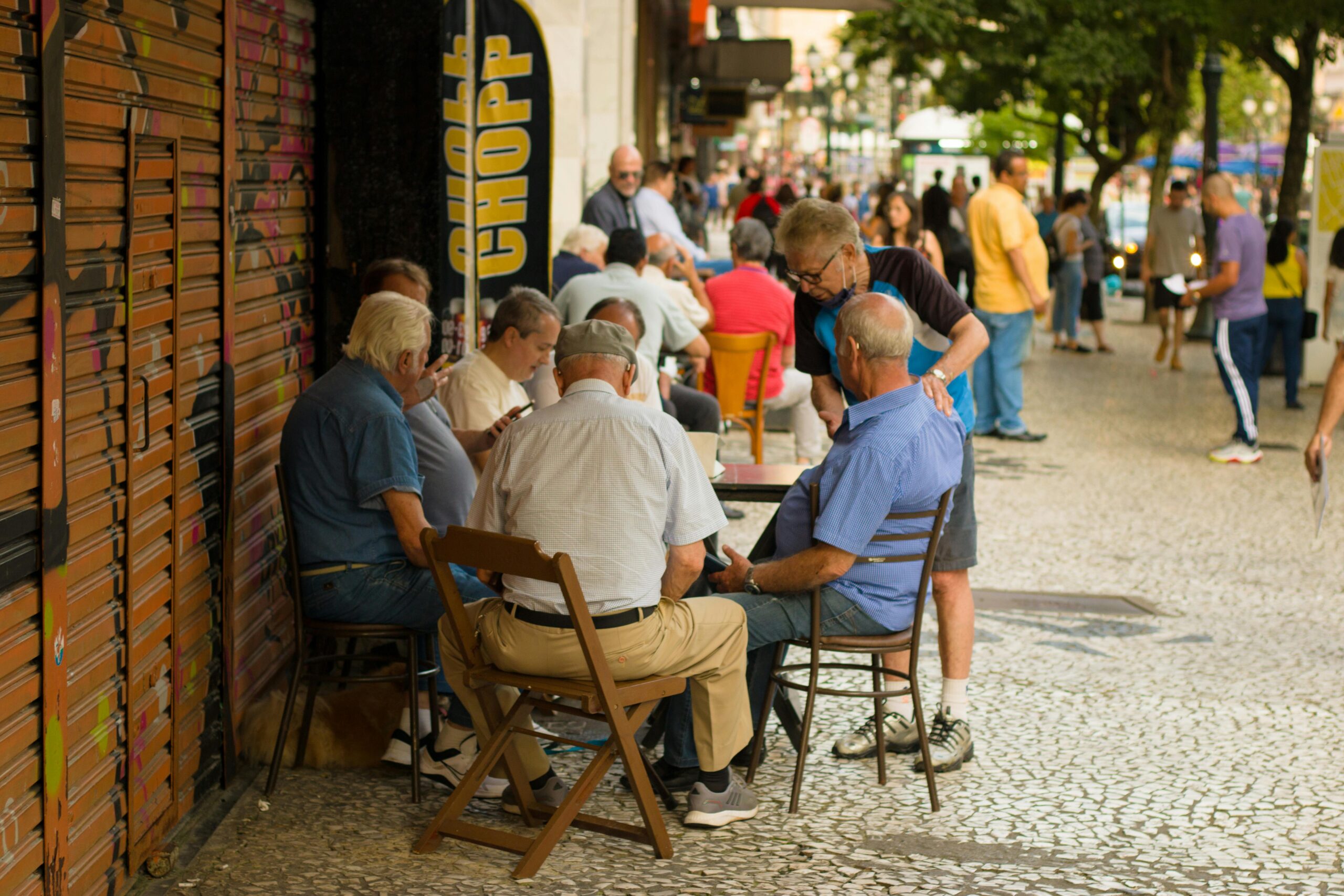 Elderly men enjoy leisure time sitting together outdoors in an urban setting, promoting social connections.