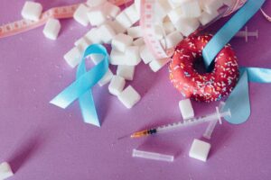 Creative composition highlighting diabetes awareness with donut, syringe, and sugar cubes on purple background.