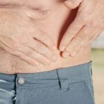 A person holding their abdomen, indicating possible discomfort or injury.