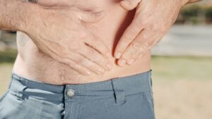 A person holding their abdomen, indicating possible discomfort or injury.